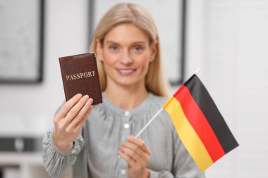 Göçmen bürosu. Pasaportu ve Almanya bayrağıyla mutlu bir kadın, seçici bir odak noktası.