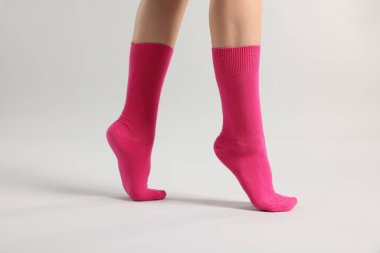 Açık gri arka planda parlak pembe çoraplı kadın, yakın plan.