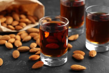 Lezzetli amaretto likörlü bardaklar ve koyu gri masada badem, yakın plan.