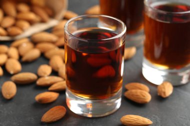 Lezzetli amaretto likörlü bardaklar ve koyu gri masada badem, yakın plan.