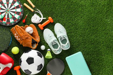 Farklı spor aletleri ve yeşil çimlerin üzerinde spor ayakkabıları, düz yatış. Metin için boşluk