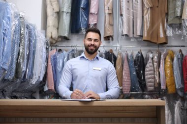 Kuru temizleme servisi. İçerideki tezgahta mutlu işçi