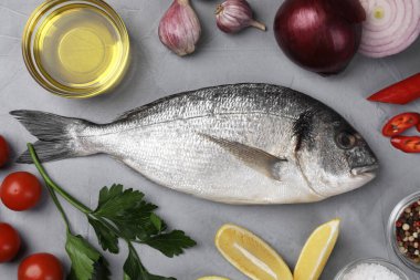 Çiğ dorado balığı ve sebzelerle bezenmiş düz bir kompozisyon.