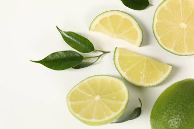 Beyaz arka planda taze limon ve yeşil yapraklar, düz uzanmış.