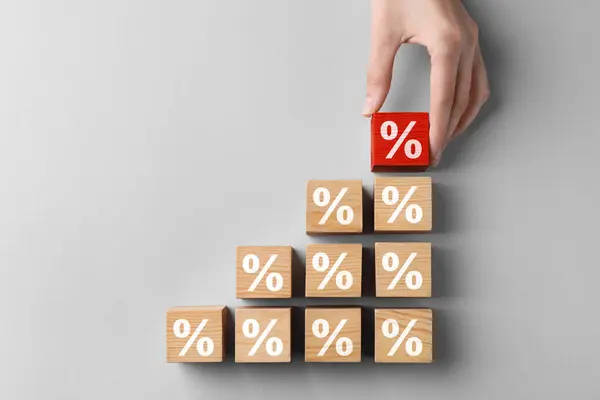 Best mortgage interest rate. Woman putting red cube with percent sign to others on light background, top view