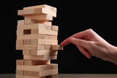 Siyah arka planda Jenga oynayan kadın, yakın plan