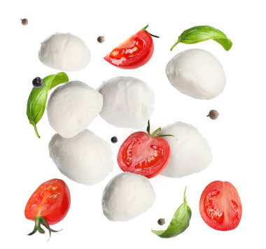 Mozzarella topları, domatesler, fesleğen yaprakları ve beyaz arka plana düşen biberler.