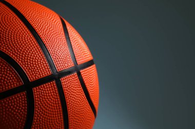 Koyu gri arka planda turuncu bir basketbol topu, yakın plan. Metin için boşluk