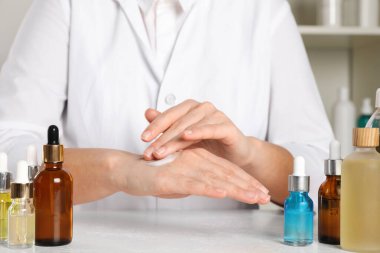 Dermatolog, kozmetik ürünlerini kapalı bir masada test ediyor.