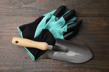 Bir çift pençe bahçe eldiveni ve tahta masanın üstünde mala.