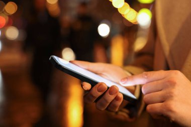 Şehir sokağında akıllı telefon kullanan kadın, yakın plan.