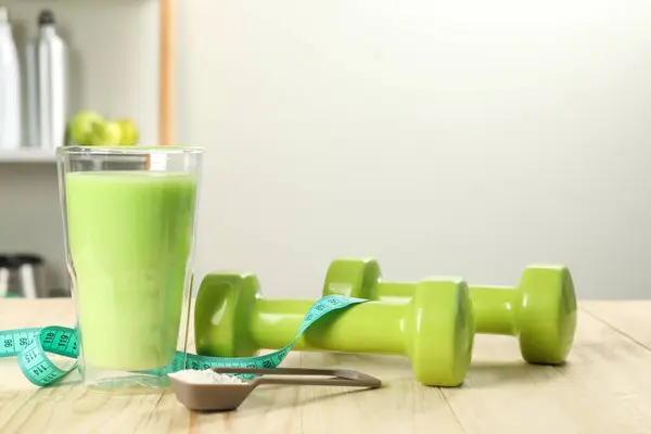 Tasty shake, dumbbells, measuring tape and powder on wooden table, space for text. Weight loss