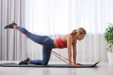 Spor yapan atletik bir kadın evde spor yaparken lastikli bant takıyor.