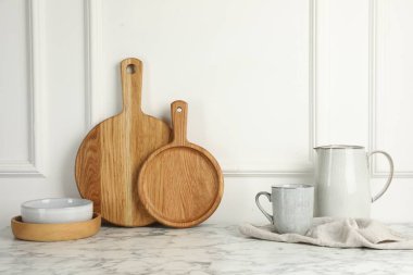 Tahta kesme tahtaları, bulaşık takımı ve havlu beyaz mermer masa üzerinde.