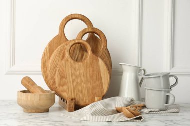 Tahta kesme tahtaları, kaşıklar ve bulaşık takımları beyaz mermer masada.