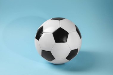 Açık mavi arka planda bir futbol topu. Spor malzemeleri.