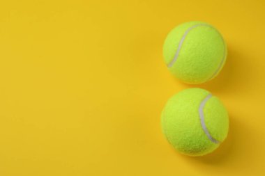 Sarı arka planda iki tenis topu, manzaranın üstünde. Metin için boşluk