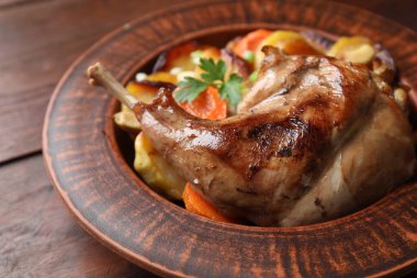 Ahşap masada sebzeli lezzetli pişmiş tavşan eti, yakın plan.