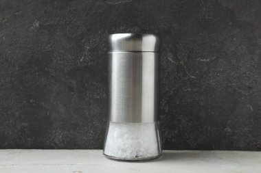 Gri arkaplana karşı hafif masada tuz karıştırıcı, yakın plan