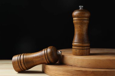 Tuz ve biber karıştırıcılar ahşap masada, siyah arka planda, yakın plan