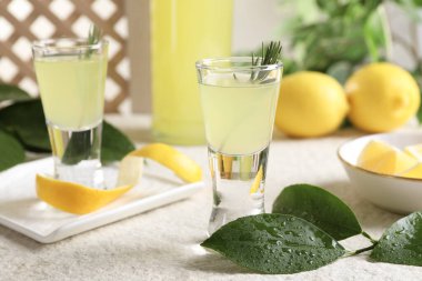 Lezzetli limoncello likörü ve yeşil yapraklar açık dokulu masa, yakın çekim