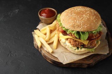 Çıtır tavuk köfteli lezzetli burger, patates kızartması ve siyah masada sos. Metin için boşluk