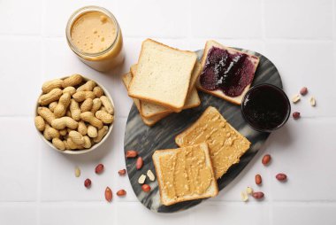 Fıstık ezmeli, fındıklı ve reçelli leziz tostlar beyaz fayanslı masada, düz yerde.