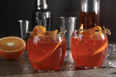 Aperol sprey kokteyli, buz küpleri ve portakal dilimleri gri desenli masada, yakın plan.
