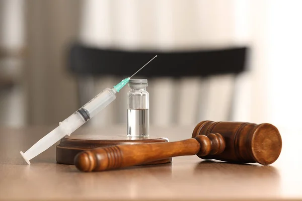 Law concept. Gavel, syringe and glass vial on wooden table