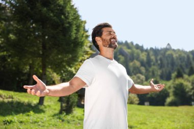 Özgürlüğü hissetmek. Güneşli bir günde kolları açık mutlu bir adam.