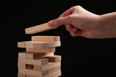 Siyah arka planda Jenga oynayan kadın, yakın plan