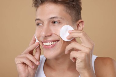 Bej arkaplanlı pamuklu yakışıklı bir adam.