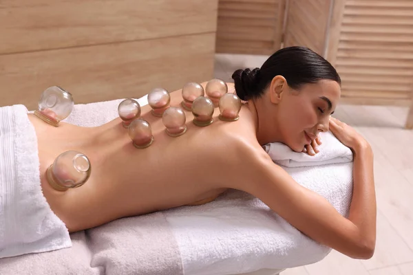 Cupping therapy. Woman with glass cups on massage couch in spa salon