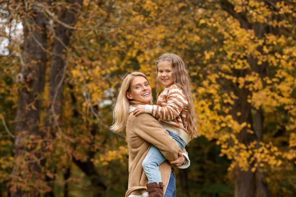Happy mother with her daughter in autumn park