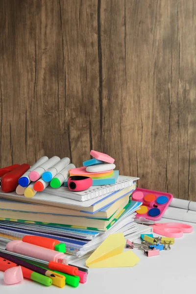 Many different books, paper plane and school stationery on white table. Back to school