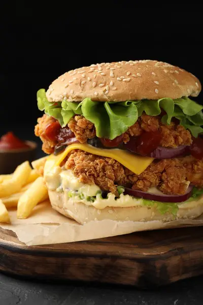 Delicious burger with crispy chicken patty and french fries on table, closeup