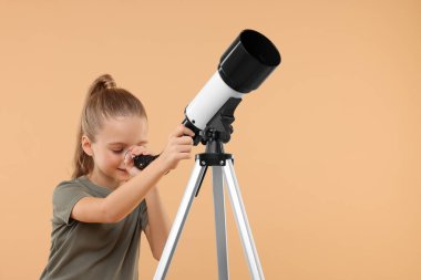 Küçük kız yıldızlara teleskopla bakıyor. Bej arka planda, mesaj için yer var.