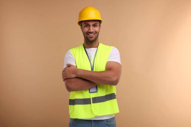 Bej arka planda kasketi ve rozeti olan mühendis.