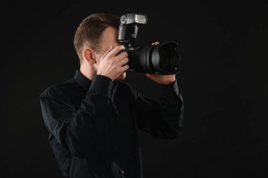 Profesyonel fotoğrafçı siyah arkaplanda fotoğraf çekiyor.
