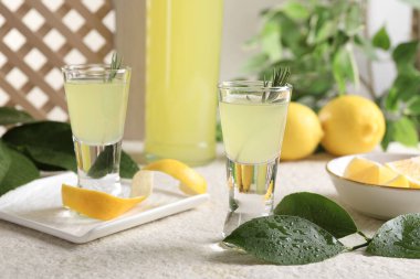 Lezzetli limoncello likörü ve yeşil yapraklar açık dokulu masa.