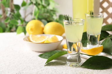 Lezzetli limoncello likörü, limon ve yeşil yapraklar beyaz desenli masada, yakın plan. Metin için boşluk