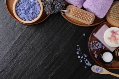 Farklı spa ürünleri ve siyah desenli masa üzerinde lavanta içeren düz kompozisyon. Metin için boşluk