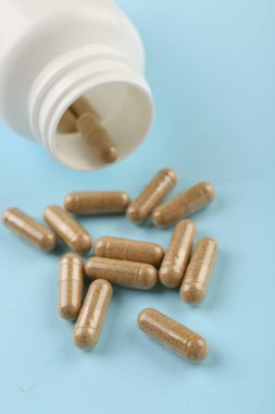 Açık mavi arka planda şişe ve vitamin kapsülleri, yakın plan