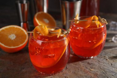 Aperol sprey kokteyli, buz küpleri ve portakal dilimleri gri desenli masada, yakın plan.