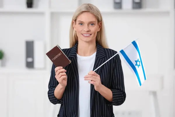 Immigration. Happy woman with passport and flag of Israel indoors