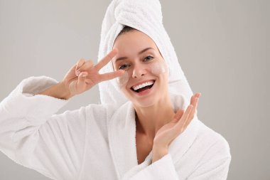 Yüzünde gri arka planda kozmetik ürünü olan bir kadın. Spa tedavileri