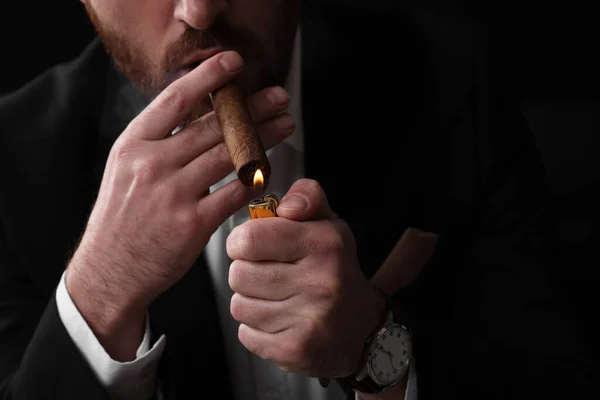 Man lightning cigar on black background, closeup