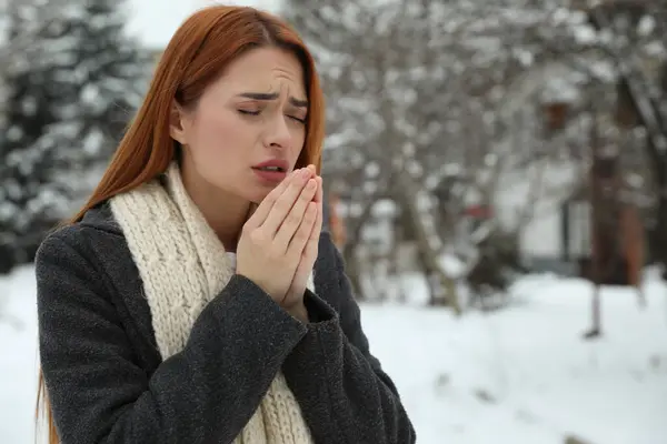 Beautiful young woman coughing outdoors, space for text. Cold symptoms