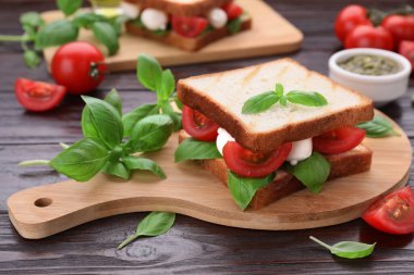 Nefis Caprese sandviçi, mozarella, domates, fesleğen ve pesto soslu ahşap masa.