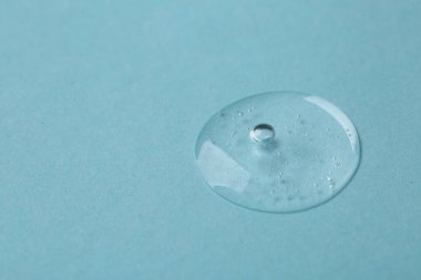Açık mavi arka planda kozmetik serumu örneği, yakın plan. Metin için boşluk